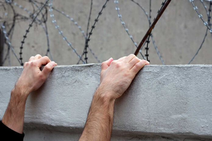 Men's,Hands,On,A,Concrete,Fence,Against,A,Background,Of