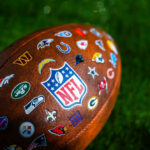 SF 49ers Player Shot NFL football with team logos on grass field.