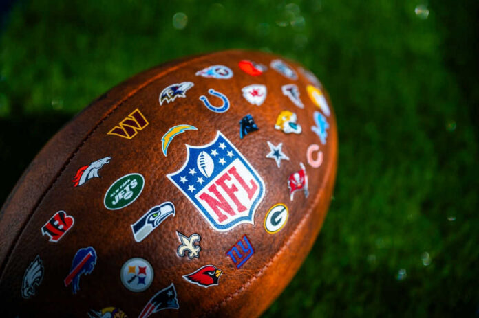 NFL football with team logos on grass field.