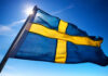 Liberal Paradise COLLAPSES—Sweden Chooses Deportation Power Swedish flag waving against a clear blue sky