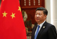 China’s Propaganda Machine in Overdrive – What’s Next? Man in suit standing next to Chinese flag