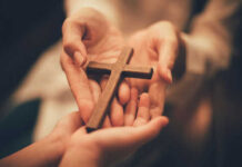 Hands holding a wooden cross together
