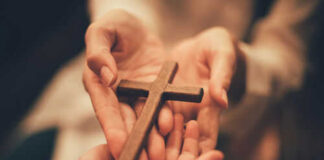 Hands holding a wooden cross together