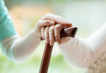 Hands resting on a wooden cane together