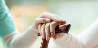 Hands resting on a wooden cane together