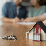 Model house and keys on a wooden table