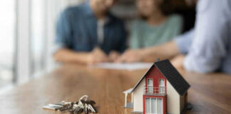 Model house and keys on a wooden table