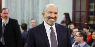 Man smiling in a suit at crowded indoor event