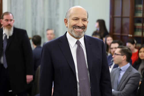Man smiling in a suit at crowded indoor event