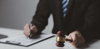 Person with gavel signing document at desk