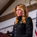 Melania at UN Helm—Can She Handle It? Woman speaking at podium with American flag background
