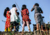 Group of children in colorful clothing standing on a ledge