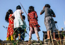 Group of children in colorful clothing standing on a ledge