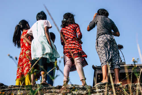 Group of children in colorful clothing standing on a ledge