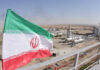 Iranian flag waving in front of an oil processing facility