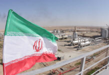 Iran Showdown: Markets Brace for Worst Iranian flag waving in front of an oil processing facility