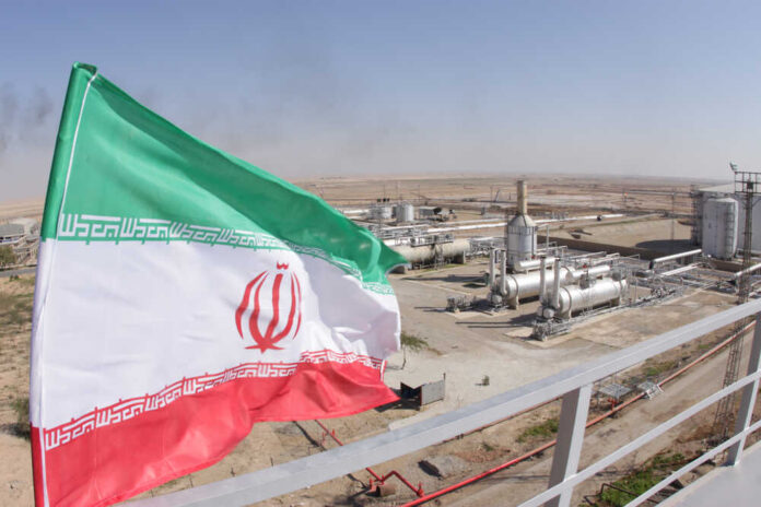 shutterstock_1227310843.jpg Iranian flag waving in front of an oil processing facility