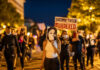 Protesters holding signs and a portrait of Breonna Taylor during a nighttime march