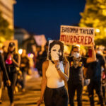 Breonna Case Collapse: DOJ’s Unexpected Decision Protesters holding signs and a portrait of Breonna Taylor during a nighttime march