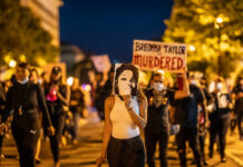 Breonna Case Collapse: DOJ’s Unexpected Decision Protesters holding signs and a portrait of Breonna Taylor during a nighttime march