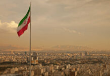 Iran’s Bold Claim: One Million Fighters Mobilized! Iranian flag waving over a city skyline with mountains in the background