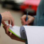 Two hands engaged in a document signing process outdoors