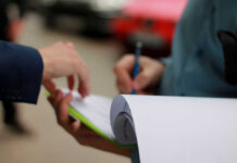 Two hands engaged in a document signing process outdoors