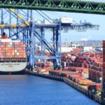 Supreme Court Slaps Down Tariff Overreach A cargo ship loaded with colorful containers docked at a busy shipping port