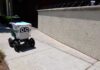 A delivery robot navigating a sidewalk in an urban area