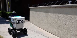 A delivery robot navigating a sidewalk in an urban area