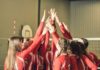 Volleyball players celebrating with hands raised together