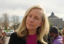 Virginia’s Governor Sparks Outrage: ICE Partnership Cut A woman with blonde hair speaking outdoors with a building in the background