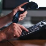 Domino’s Greeting on HHS Line Stuns Activists Person dialing a phone while holding the receiver