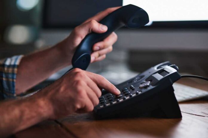 Person dialing a phone while holding the receiver