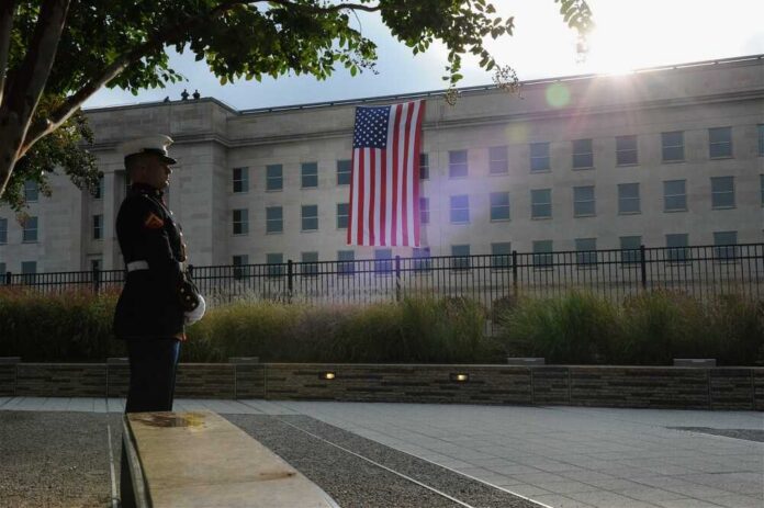 A Marine standing guard in front of the Pentagon with an American flag in the background