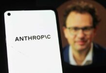 Close-up of a smartphone displaying the word 'ANTHROPIC' with a blurred portrait in the background