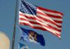 American flag and Michigan state flag flying against a blue sky