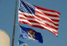 Imam’s Praise for Khamenei Shocks Michigan American flag and Michigan state flag flying against a blue sky