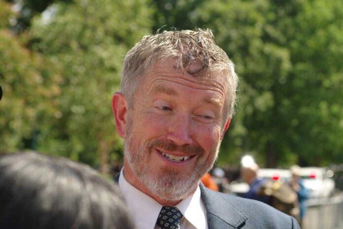A smiling man in a suit engaging in conversation outdoors