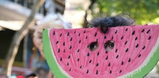 Child wearing a watermelon mask at a festive event