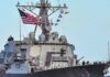 A naval destroyer displaying the American flag and various signal flags