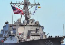 A naval destroyer displaying the American flag and various signal flags