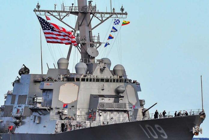 A naval destroyer displaying the American flag and various signal flags
