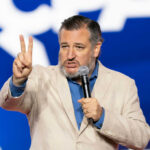 Man speaking on stage in front of blue background