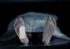 Feet with tag under white sheet in morgue