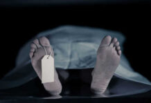 Feet with tag under white sheet in morgue