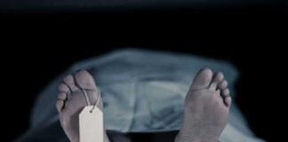 Feet with tag under white sheet in morgue