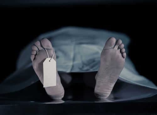 Feet with tag under white sheet in morgue