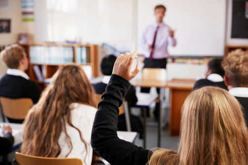 Classroom with student raising hand teacher speaking front