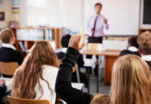 Classroom with student raising hand teacher speaking front